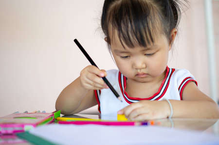 A young Asian female toddler with black hair is smiling.She happily with Colored pencils.And copy space.の写真素材
