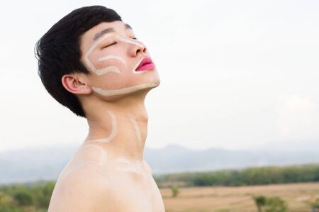 One Asian gay handsome man not wearing a shirt, he writes on the face and wears pink lipstick. Copy spaceの写真素材
