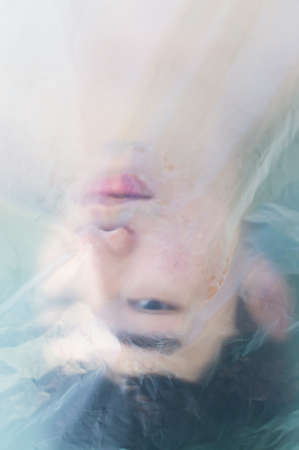 Asian gay man is wearing a plastic bag on his head that has suffocated a concept to stop using plastic and environmental pollution or stops marine and world pollution.And copy space.の写真素材