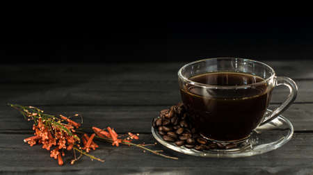 Hot coffee in a coffee cup and roasted coffee beans with a dark tone wood floor. And there is a copy space.の写真素材
