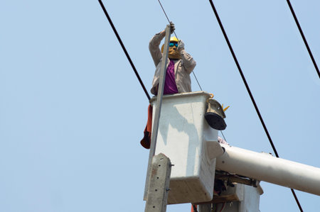 Electricians work together on the electric cable car and electric pole. To maintain the high and low...