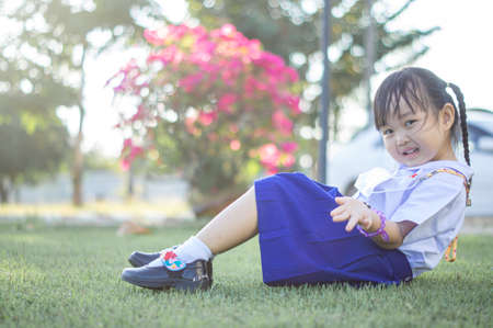 PHRAE, THAILAND â NOVEMBER 20: Asian girl in kindergarten uniforms relaxes outside the building on the December 20,2021 in PHRAE,TH.のeditorial素材