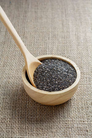 Chia seed in a wooden cup against burlap backgroundの写真素材