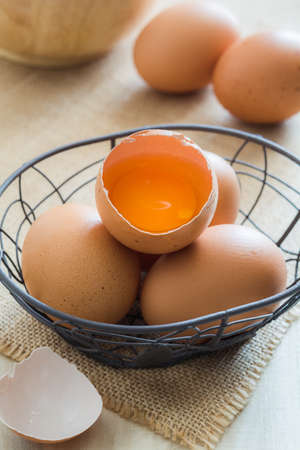 Broken chicken eggs in basket on wooden backgroundの写真素材