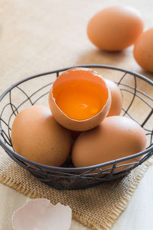 Broken chicken eggs in basket on wooden backgroundの写真素材