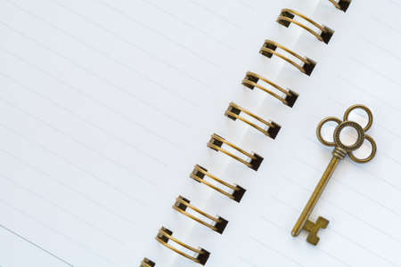 A gold metal key on white paperの写真素材