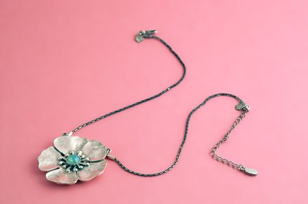 Silver flower necklace, on pink background.の写真素材