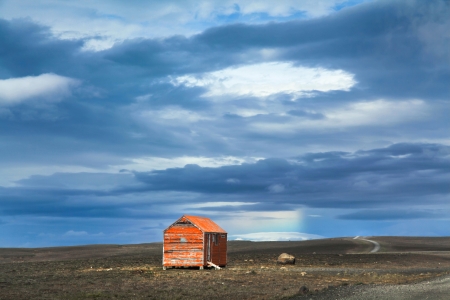 Panoramic view of barren landscape with old red snowstorm shelter at Kjolur highland road, Icelandの写真素材