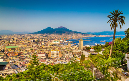 Scenic picture-postcard view of the city of Napoli with famous Mount Vesuvius in the background in golden evening light at sunset, Campania, Italyの写真素材