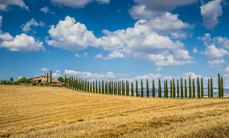 Beautiful Tuscany landscape with traditional farm house and dramatic clouds on a sunny day in Val d Orcia, Tuscany, Italyの写真素材