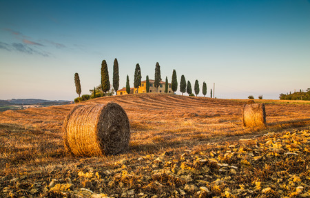 Beautiful Tuscany landscape with traditional farm house and hay bales in golden evening light, Val d Orcia, Tuscany, Italyの写真素材