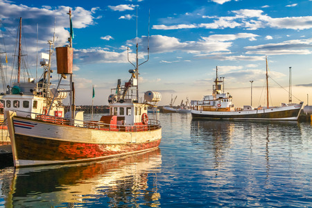Panoramic view of traditional old wooden fisherman boats lying in harbor in beautiful golden evening light at sunset, town of Husavik, Skjalfandi Bay, Iceland, northern Europeの写真素材