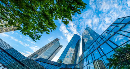 Bottom view of modern skyscrapers in business district against blue skyの写真素材