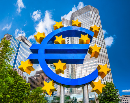 Euro sign at European Central Bank headquarters in Frankfurt, Germany with dark dramatic clouds symbolizing a financial crisis