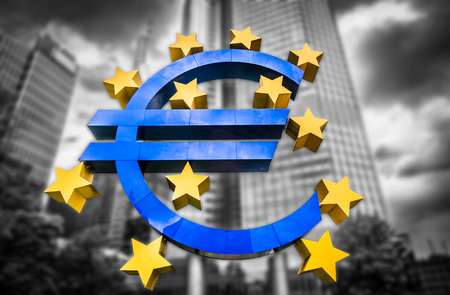 Euro sign at European Central Bank headquarters in Frankfurt, Germany on abstract blurred background of dark dramatic clouds symbolizing a financial crisisの写真素材
