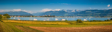 Beautiful panoramic view of boats lying in Lake Zurich with the historic town of Rapperswil in the background in golden evening light at sunset in summer, Rapperswil-Jona, canton of St. Gallen, Switzerlandの写真素材