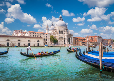 Beautiful view of traditional Gondolas on Canal Grande with historic Basilica di Santa Maria della Salute in the background on a sunny day in Venice, Italyの写真素材