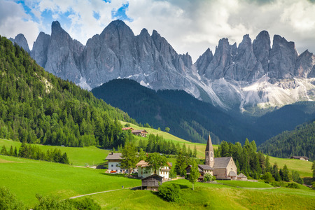 Beautiful view of idyllic mountain scenery in the Dolomites with famous Santa Maddelana mountain village on a sunny day with blue sky and clouds in spring, Val di Funes, South Tyrol, northern Italyの写真素材