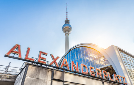 Wide-angle view of Alexanderplatz neon sign with famous TV tower and train station in golden evening light at sunset in summer, central Berlin Mitte district, Germanyのeditorial素材