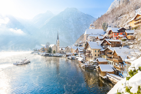 Classic postcard view of famous Hallstatt lakeside town in the Alps with passenger ship on a beautiful cold sunny day with blue sky and clouds in winter, Salzkammergut region, Austria