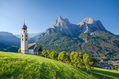 Panoramic view of idyllic mountain scenery in the Dolomites with St. Valentin Church and famous Mount Sciliar in beautiful morning light at sunrise, village of Seis am Schlern, South Tyrol, Italyの写真素材