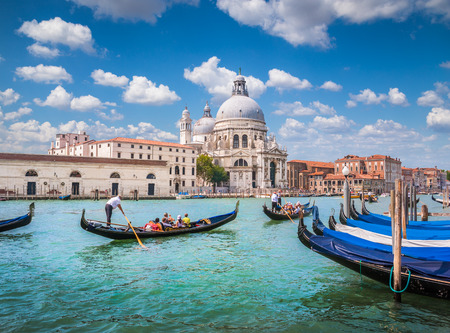 Beautiful view of traditional Gondolas on Canal Grande with historic Basilica di Santa Maria della Salute in the background on a sunny day in Venice, Italyの写真素材