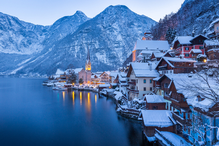 Classic postcard view of famous Hallstatt lakeside town in the Alps with beautiful Hallstattersee in mystical post sunset twilight during blue hour at dusk in winter, Salzkammergut, Austriaの写真素材