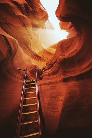 Beautiful view of amazing sandstone formations with a ladder leading toward a magic light beam in famous Antelope Canyon near the historic town of Page at Lake Powell, American Southwest, Arizona, USAの写真素材