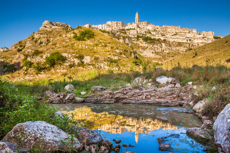 Classic view of the ancient town of Matera (Sassi di Matera), European Capital of Culture 2019, in beautiful golden morning light with blue sky reflecting in lake, Basilicata, southern Italyの写真素材