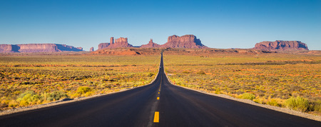 Classic panorama view of historic U.S. Route 163 running through famous Monument Valley in beautiful golden evening light at sunset on a beautiful sunny day with blue sky in summer, Utah, USAの写真素材