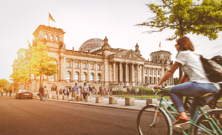 Urban city life with famous Reichstag building in the background in beautiful golden evening light at sunset in summer with retro vintage style pastel toned filter effect, Berlin, Germany