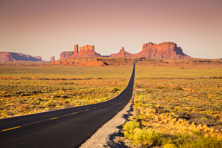 Classic panorama view of historic U.S. Route 163 running through famous Monument Valley in beautiful golden evening light at sunset on a beautiful sunny day with blue sky in summer, Utah, USAの写真素材