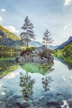 Beautiful scene of trees on a rock island in idyllic scenery at charming Lake Hintersee with blue sky and clouds in summer, Nationalpark Berchtesgadener Land, Upper Bavaria, Germanyの写真素材