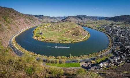 Panoramic view of ship on famous Moselle river at Moselschleife with the historic town of Bremm on a beautiful sunny day with blue sky in springtime, Rheinland-Pfalz, Germanyの写真素材