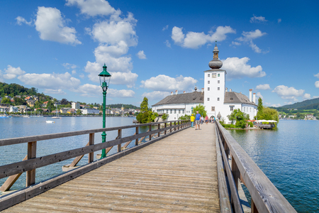 Beautiful view of famous Schloss Ort with wooden bridge at Lake Traunsee on a sunny day with blue sky and clouds in summer, Gmunden, Salzkammergut region, Austriaのeditorial素材