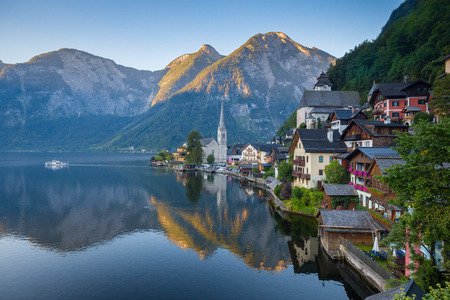 Classic postcard view of famous Hallstatt lakeside town in the Alps with traditional passenger ship in early morning lightの写真素材