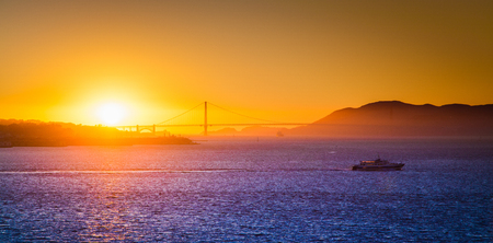 Panoramic view of famous Golden Gate Bridge illuminated in beautiful golden evening light at sunset in summerの写真素材