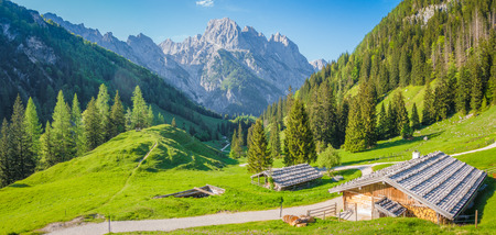 Idyllic landscape in the Alps with traditional mountain chalets and fresh green mountain pastures in summerの写真素材