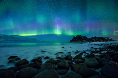Amazing Aurora Borealis dancing over famous Uttakleiv Beach during a cold arctic night on Lofoten Islands archipelago in winterの写真素材