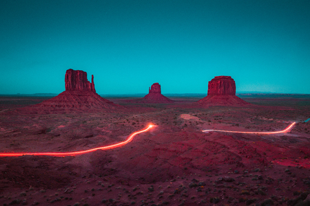 Classic panoramic view of scenic Monument Valley with the famous Mittens and Merrick Butte with light trails at night in summer, Arizona, American Southwest, USAの素材 [FY310119086992]