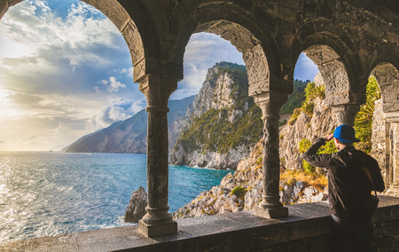 Young man enjoying scenic ocean view during sunset at famous gothic Church of St. Peter (Chiesa di San Pietro) in the town of Porto Venere with retro vintage retro style pastel toned filter effect, Ligurian Coast, province of La Spezia, Italyの写真素材