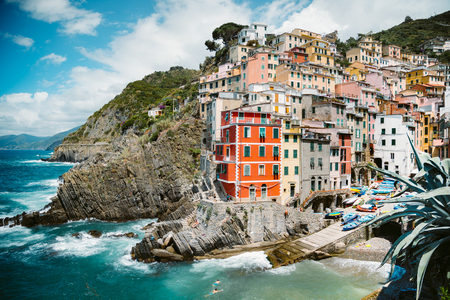 Classic view of beautiful Riomaggiore, one of the five famous picturesque fisherman villages of Cinque Terre, on a sunny day with blue sky and clouds in summer, Liguria, Italyの写真素材