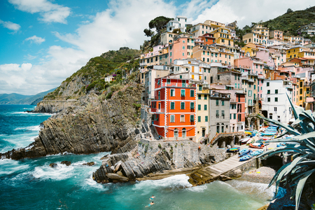 Classic view of beautiful Riomaggiore, one of the five famous picturesque fisherman villages of Cinque Terre, on a sunny day with blue sky and clouds in summer, Liguria, Italyの写真素材