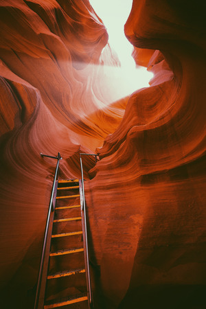 Beautiful view of amazing sandstone formations with a ladder leading toward a magic light beam in famous Antelope Canyon near the historic town of Page at Lake Powell, American Southwest, Arizona, USAの写真素材
