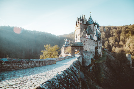 Beautiful view of famous Eltz Castle in scenic golden morning light at sunrise with blue sky on a sunny day in fall with retro vintage VSCO style filter effect, Wierschem, Rheinland-Pfalz, Germanyのeditorial素材