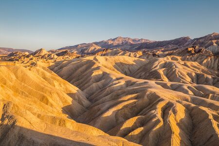 Scenic panoramic view of amazing sandstone formations at famous Zabriskie Point viewpoint in beautiful golden evening light at sunset, Death Valley National Park, California, USAの写真素材