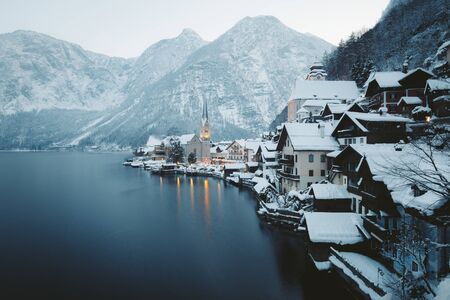 Classic postcard view of famous Hallstatt lakeside town in the Alps with beautiful Hallstattersee in mystical post sunset twilight during blue hour at dusk in winter, Salzkammergut, Austriaの写真素材