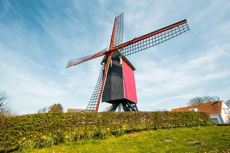 Beautiful view of traditional red wooden windmill against a blue sky with clouds in summerの写真素材