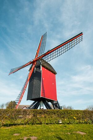 Beautiful view of traditional red wooden windmill against a blue sky with clouds in summerの写真素材