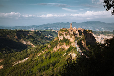Beautiful view of famous Civita di Bagnoregio with Tiber river valley and dramatic cloudscape at sunset, Lazio, Italyの写真素材